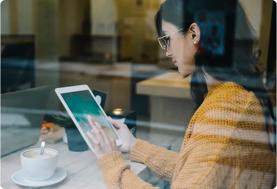 woman with coffee tapping tablet